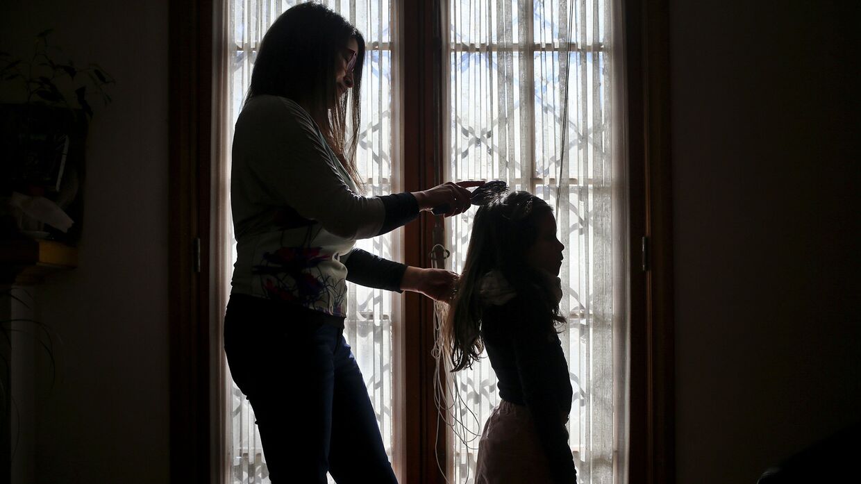 Моника Флорес расчесывает волосы ребенку-трансгендеру у себя дома в Сантьяго