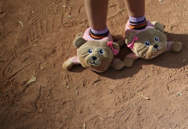 Игрушечная обувь на ногах ребенка из каравана мигрантов, направляющихся из Центральной Америки в США