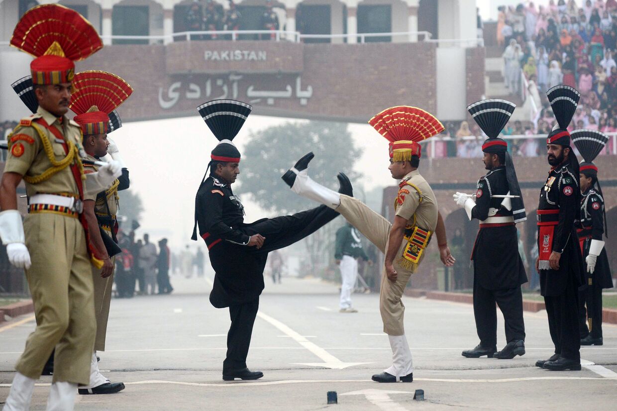 Пакистанские рейнджеры и бойцы войск пограничной безопасности Индии во время ежедневной церемонии спуска флагов в Вагахе