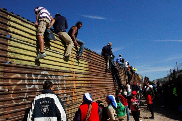 Нелегальные мигранты пересекают границу в Тихуане, Мексика