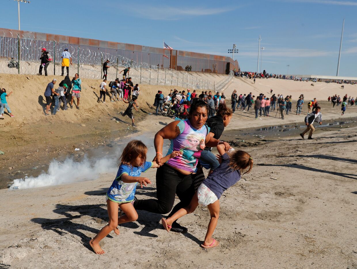Мигранты из Гондураса бегут от слезоточивого газа, распыленного американскими пограничниками. 26 ноября 2018