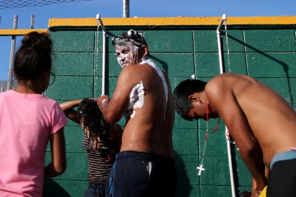 Участники каравана мигрантов принимают душ во временном приюте в Тихуане, Мексика