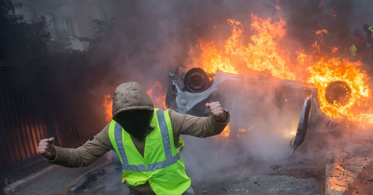 Автомобиль, горящий во время протестной акции движения автомобилистов желтые жилеты