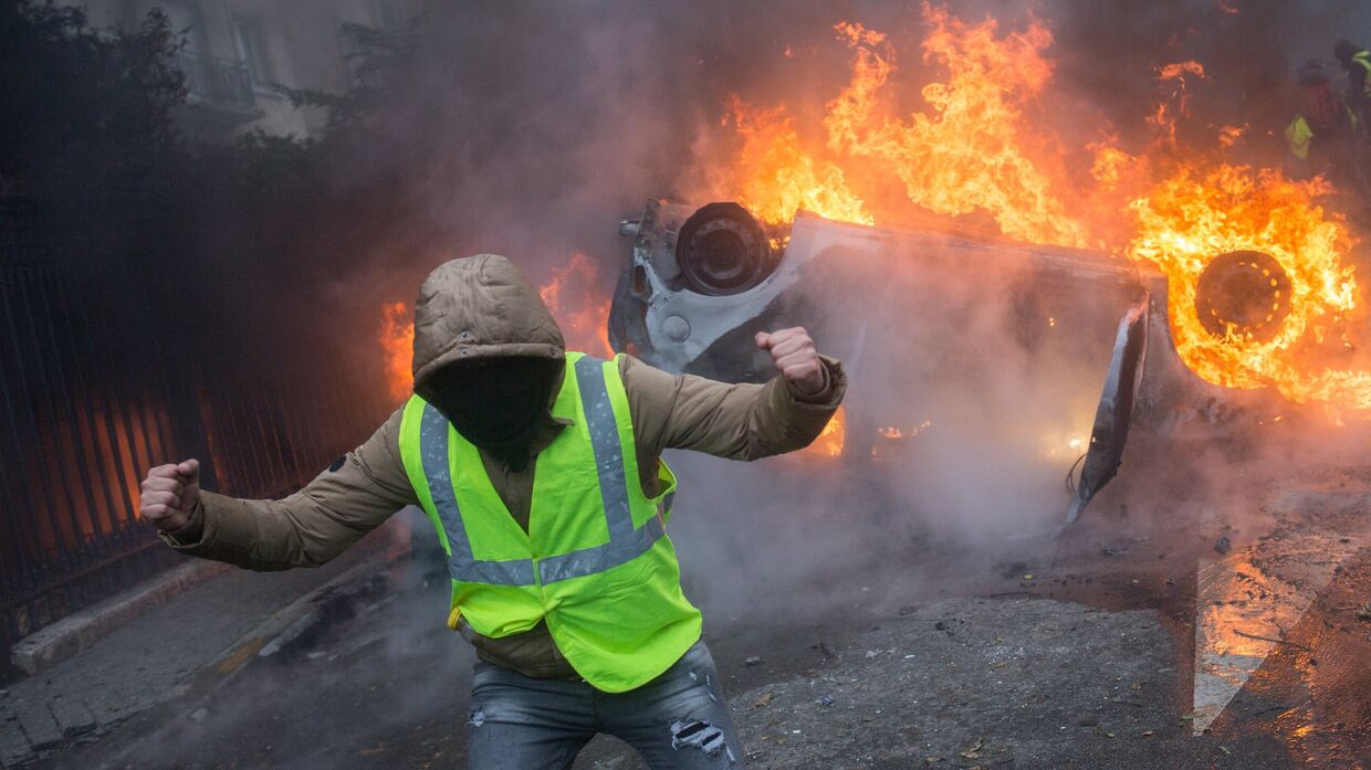 Автомобиль, горящий во время протестной акции движения автомобилистов желтые жилеты