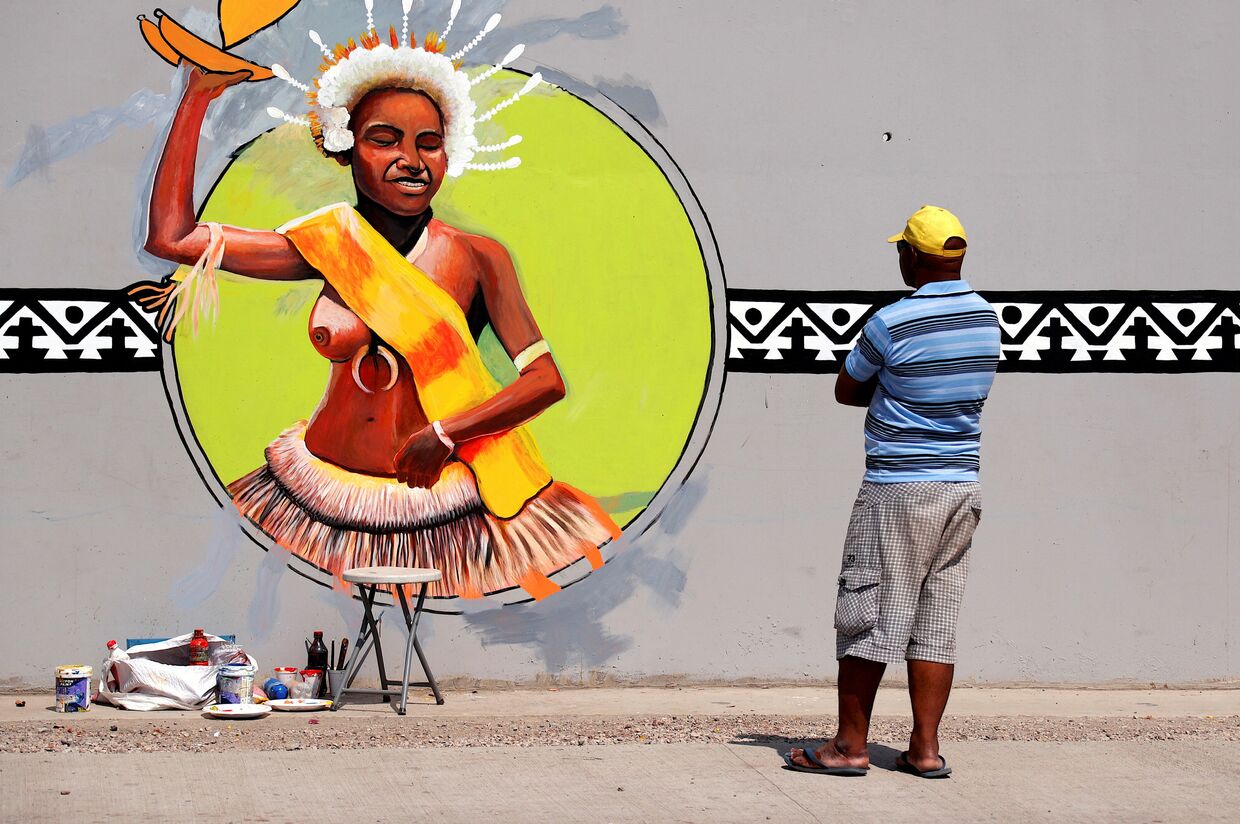Местный художник наносит последние штрихи на фреску в рамках подготовки к форуму АТЭС в Порт-Морсби