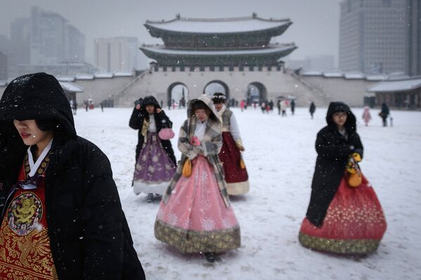 Посетители, одетые в традиционные платья ханбок во дворце Кенбоккун в Сеуле