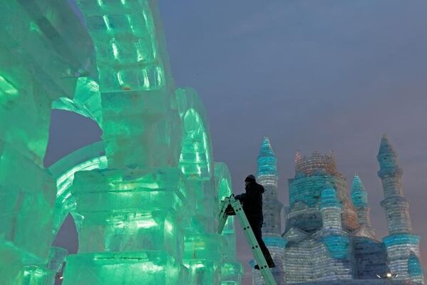 Скульптор по льду подготавливает один из экспонатов на фестивале льда