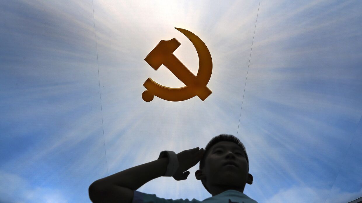 Ребенок у логотипа Коммунистической партии в военном музее в Пекине