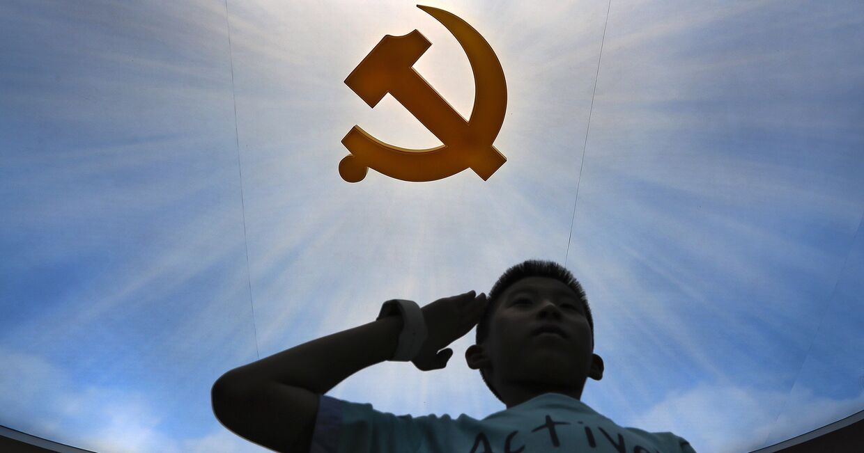 Ребенок у логотипа Коммунистической партии в военном музее в Пекине