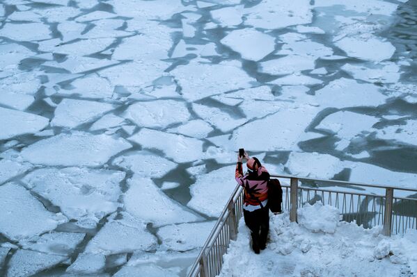 Прохожий фотографирует последствия снежного шторма и экстремально низких температур в Чикаго