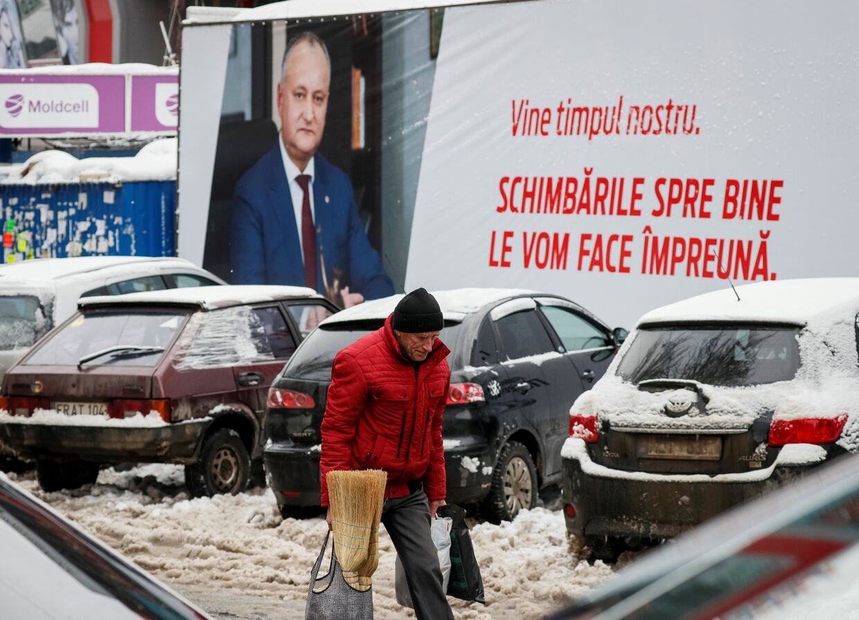 Мужчина идет возле плаката gрезидента Республики Молдова Игоря Додона в центре Кишинева
