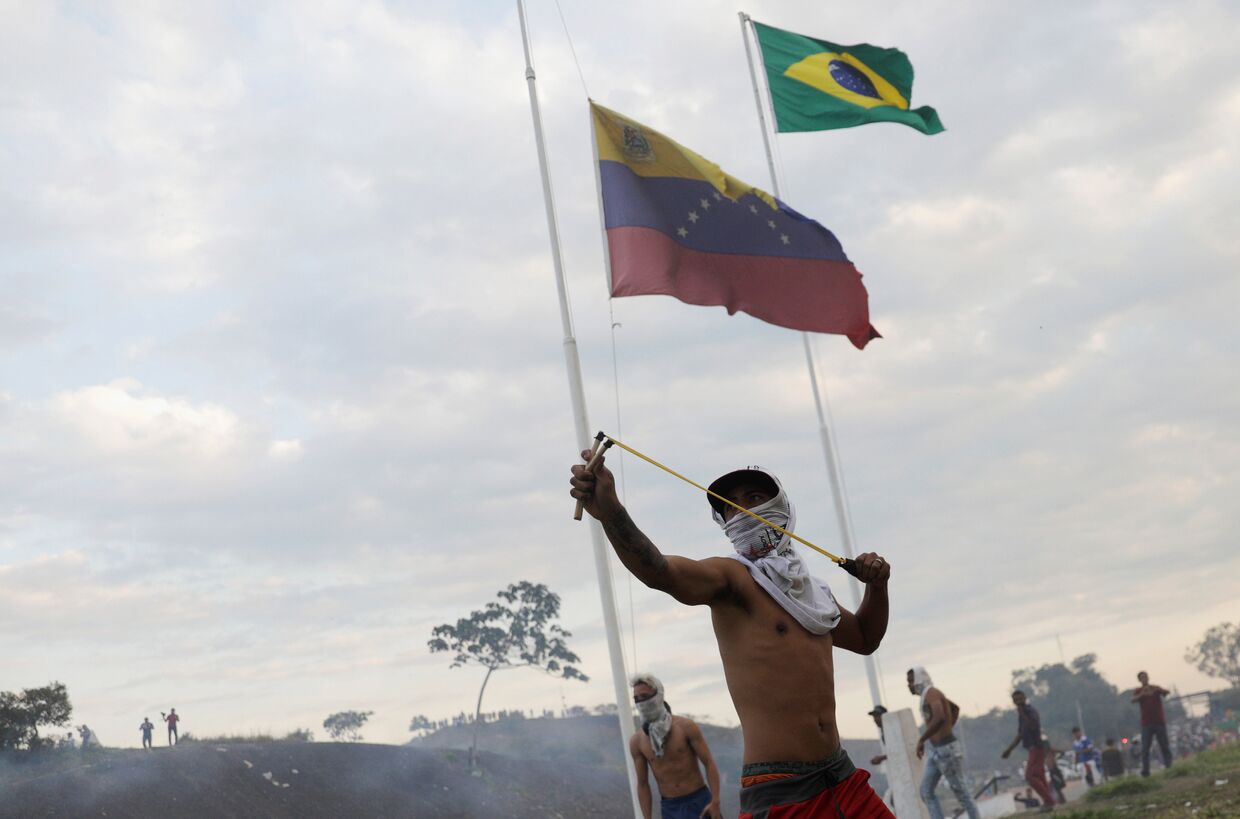 Протестующий во время столкновений с венесуэльскими солдатами у границы между Венесуэлой и Бразилией
