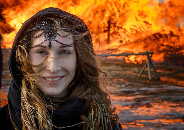 Девушка перед горящей крепостью Бастилия во время празднования Масленицы в Никола-Ленивце