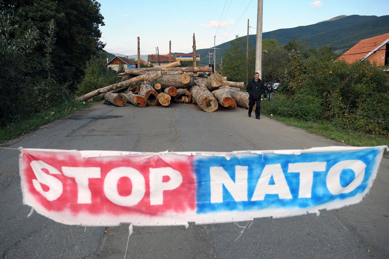 Плакат и заблокированная дорога в знак протеста против НАТО в деревне Зупце на севере Косово