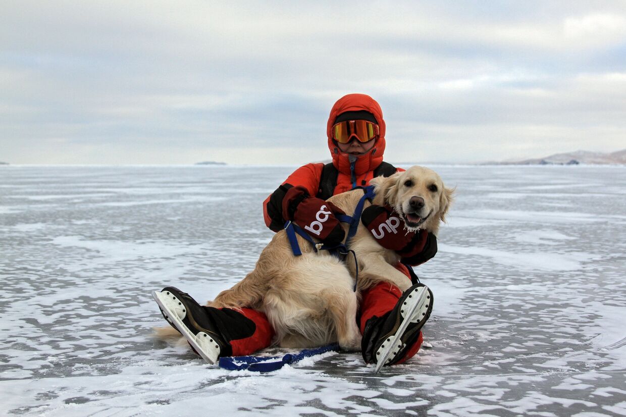 Турист с собакой породы ретривер на льду замерзшего озера Байкал