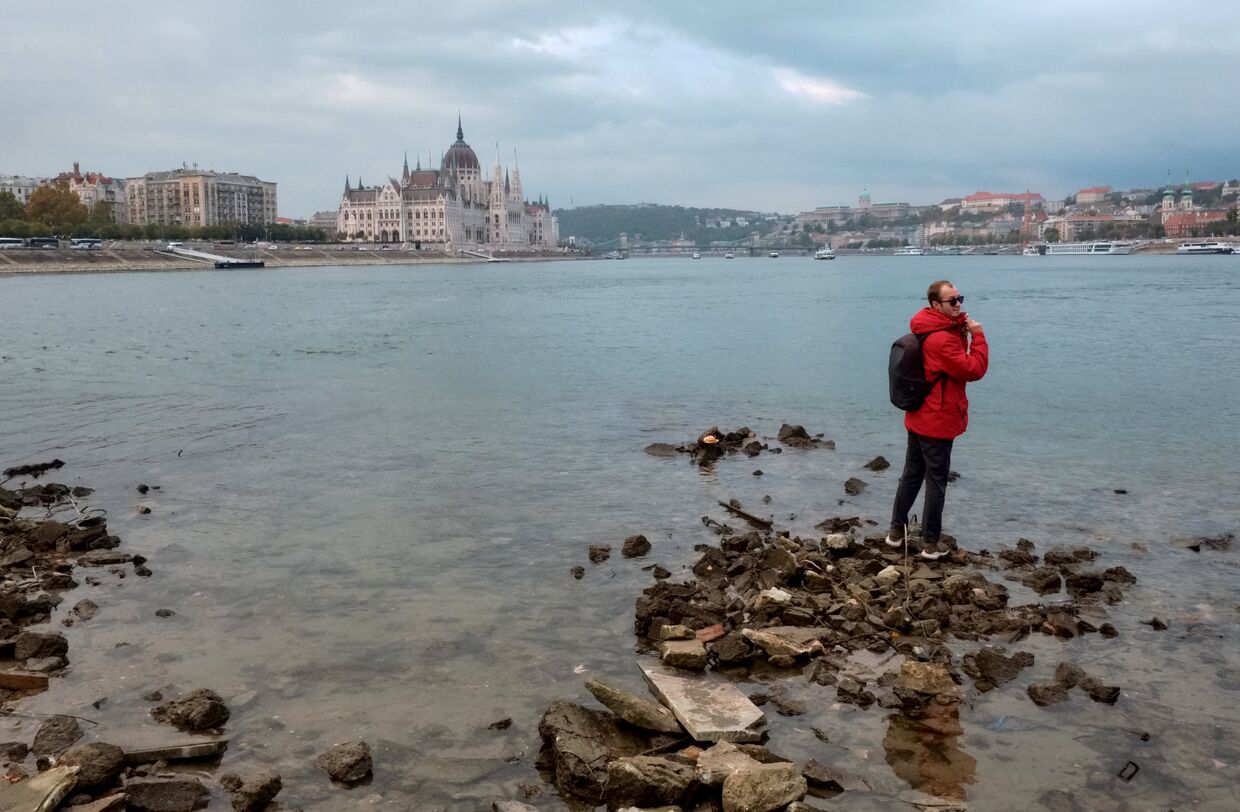 Молодой человек стоит на берегу Дуная в Будапеште
