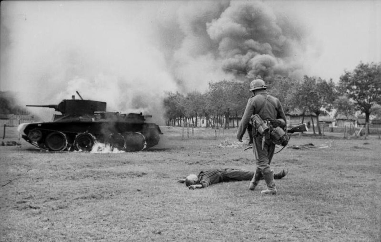 Немецкий пехотинец возле горящего советского танка БТ-5