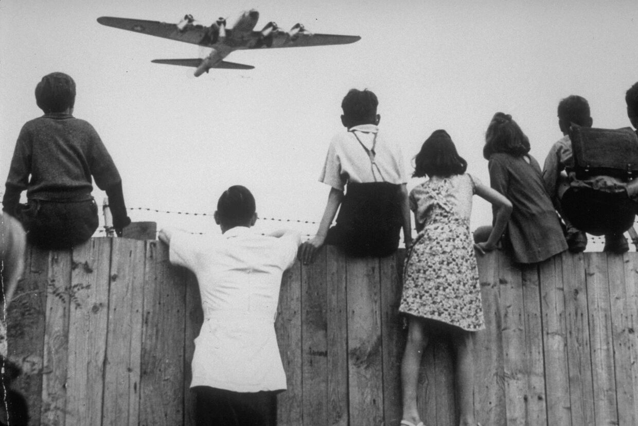 1 августа 1948. Дети из Западного Берлина смотрят, как в аэропорту Темпельхоф заходит на посадку самолет с продовольствием