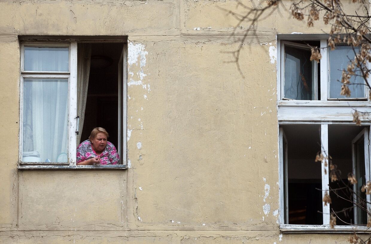 Женщина в окне пятиэтажного жилого дома