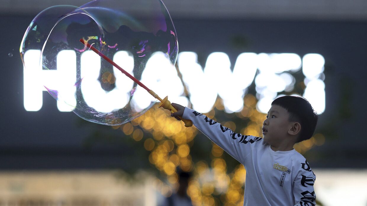 Мальчик играет с мыльными пузырями возле магазина Huawei в Пекине