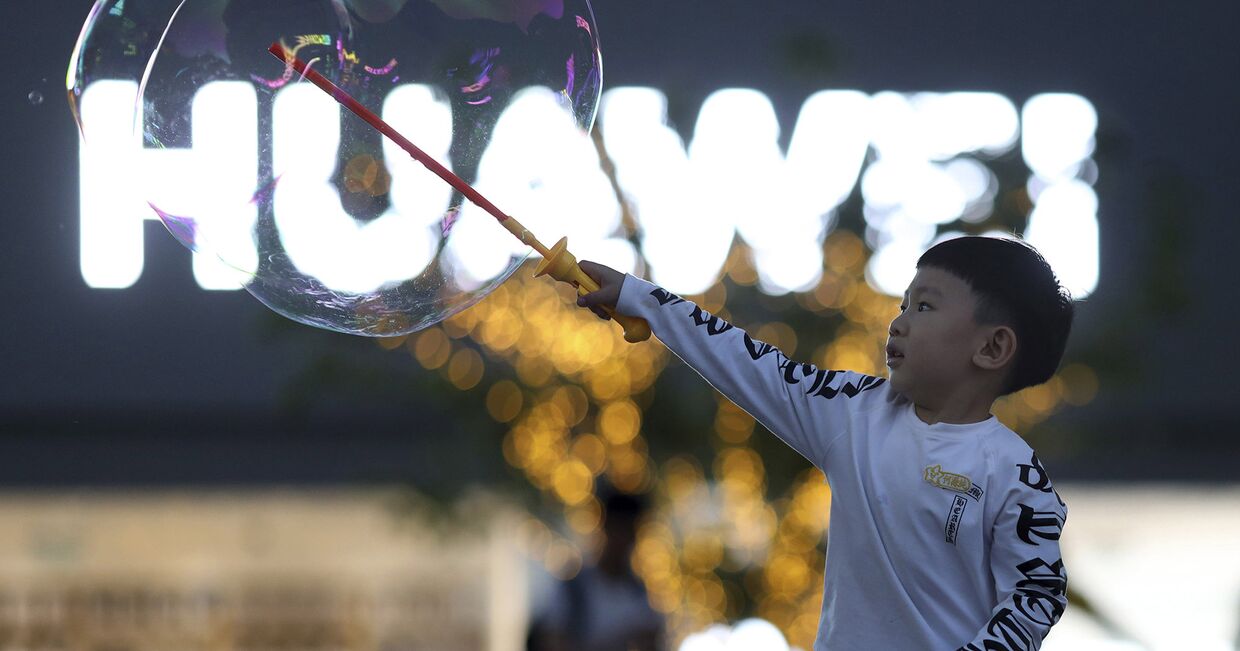 Мальчик играет с мыльными пузырями возле магазина Huawei в Пекине