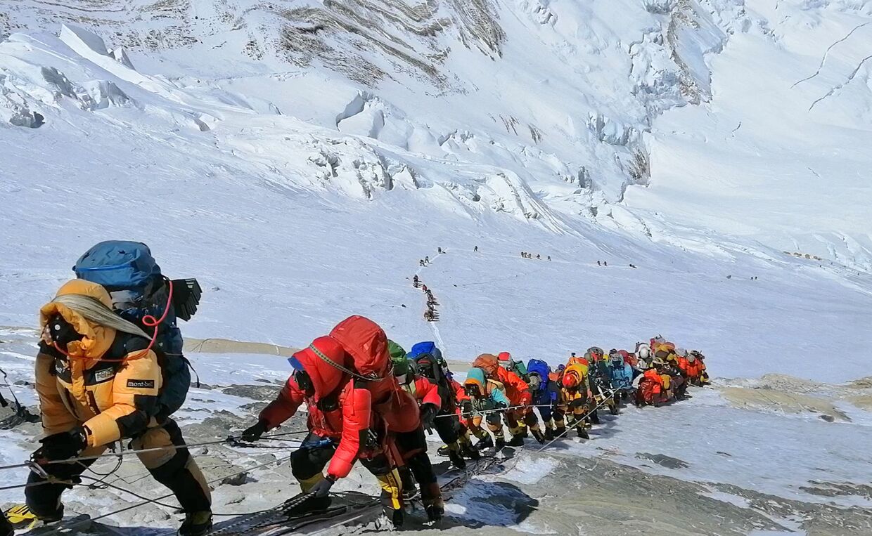 Цепочка альпинистов идет по тропе к вершине Эвереста