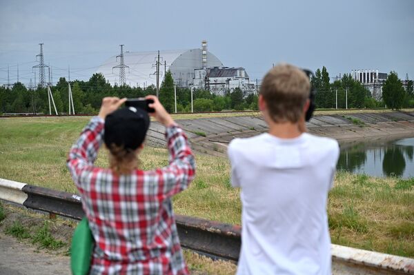 Люди фотографируют Чернобыльскую АЭС во время экскурсии