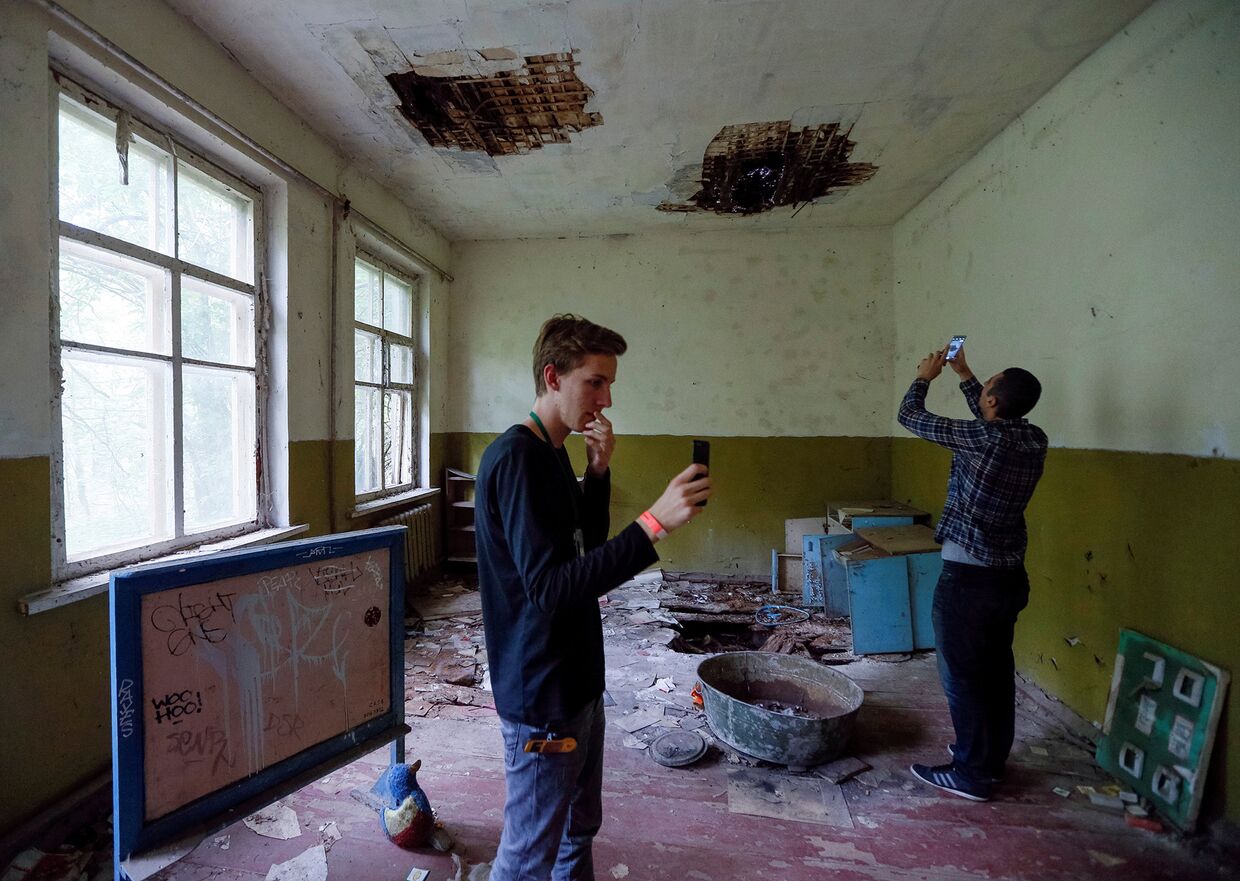 Туристы фотографируются в детском саду в заброшенном селе Копачи недалеко от Чернобыльской АЭС