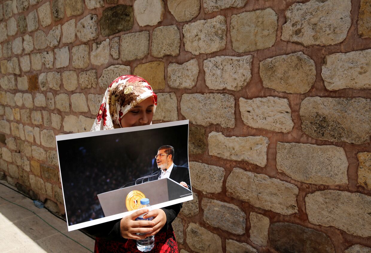 Женщина с портретом бывшего президента Египта Мохаммада Мурси на символической поминальной молитве в Стамбуле, Турция