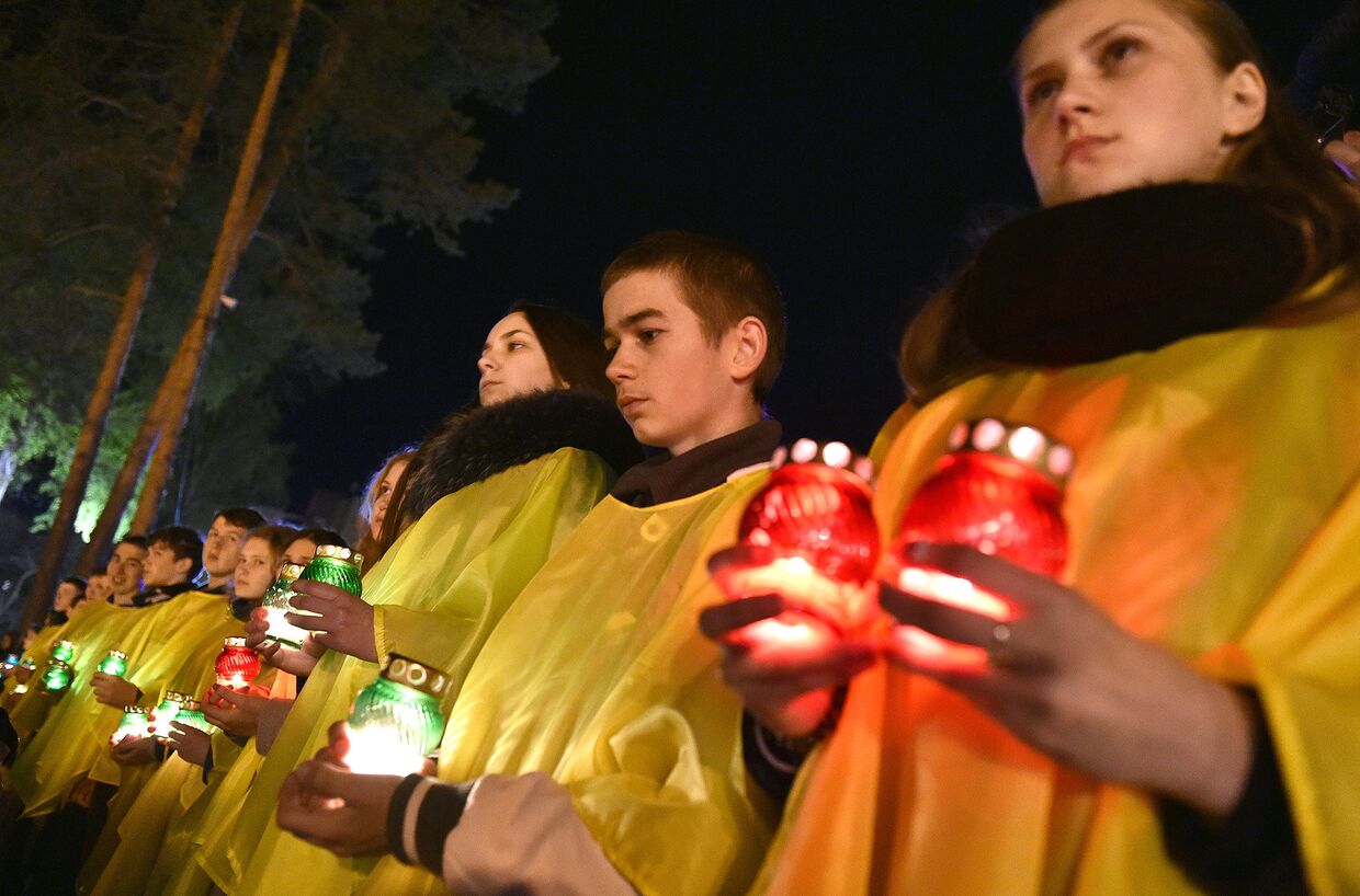 Украинцы держат свечи перед памятником чернобыльцам в Славутиче, Украина
