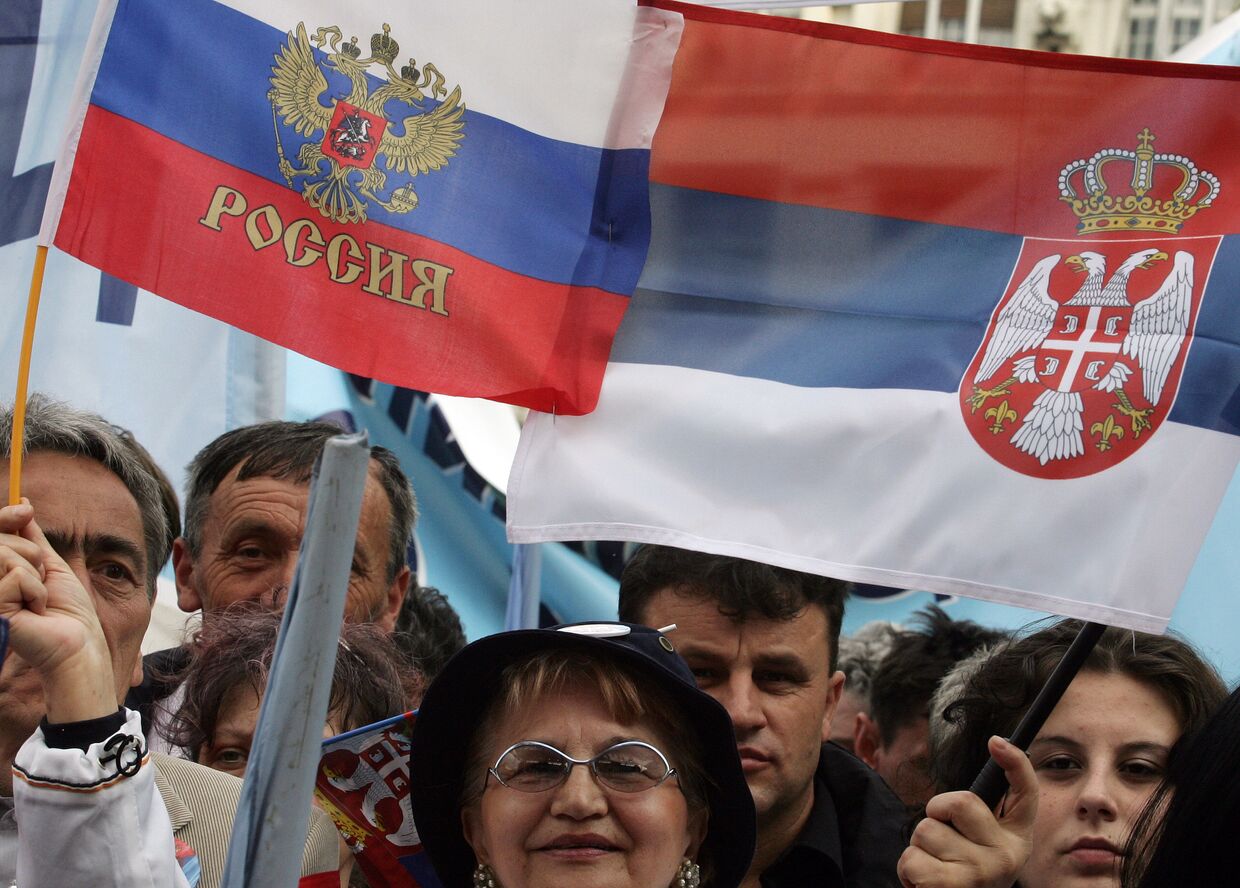 Сторонники премьер-министра Сербии Воислава Коштуницы держат российский и сербский флаг во время предвыборного митинга в Белграде