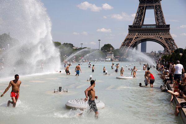 Люди охлаждаются в фонтанах Трокадеро у Эйфелевой башни в Париже