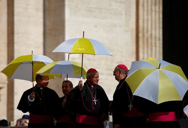 Священнослужители держат зонтики спасаймь от жары на площади Святого Петра в Ватикане