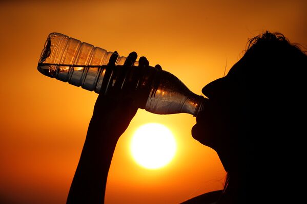 Женщина пьет воду во время экстремальной жары в Кагникорте, Франция