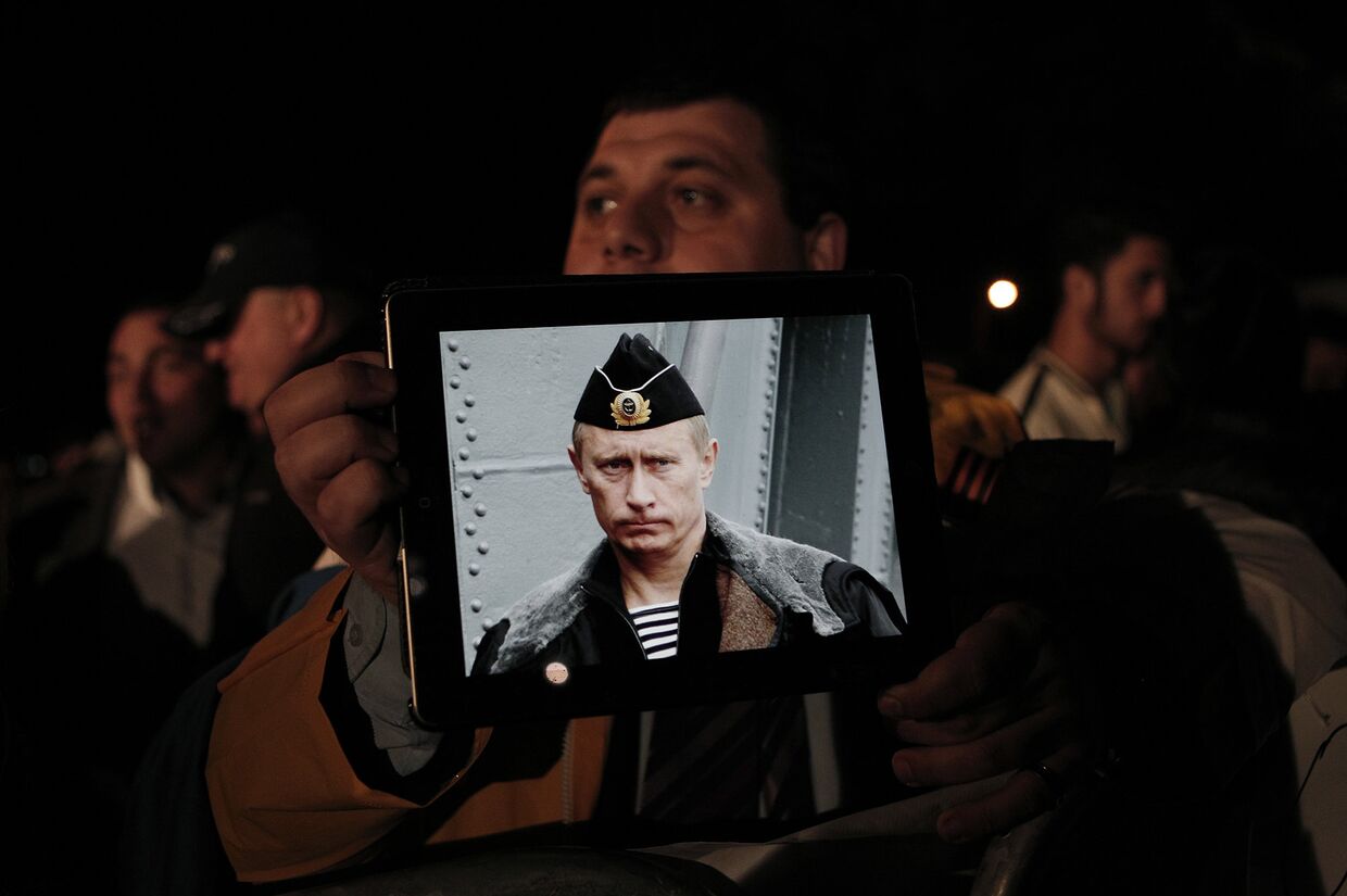 Протестующие с фотографией президента России Владимира Путина во время акции протеста у здания кипрского парламента