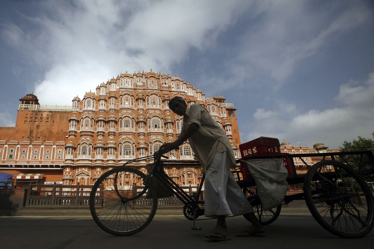 Велорикша проезжает мимо Дворца ветров в Джайпуре, Индия