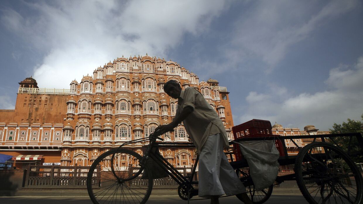 Велорикша проезжает мимо Дворца ветров в Джайпуре, Индия