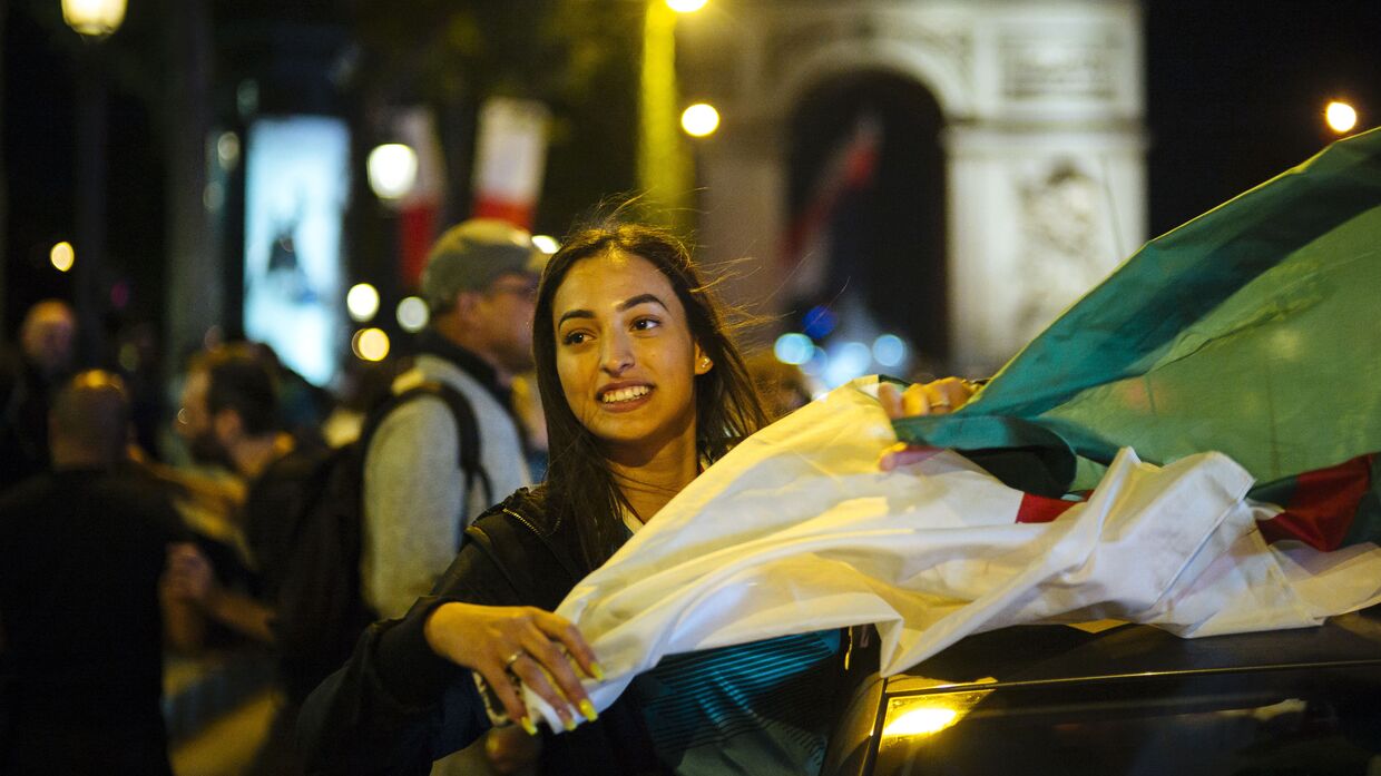Девушка с флагом Алжира у Триумфальной арки в Париже