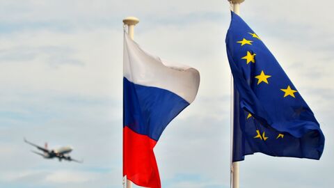 Флаги России, ЕС и Франции на набережной Ниццы. На дальнем плане - самолет заходит на посадку в международный аэропорт Ниццы.