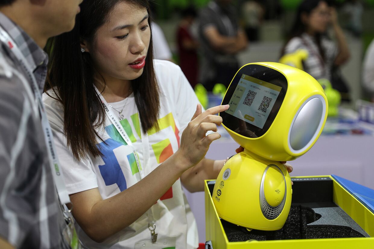 Посетители изучают робота на китайской международной выставке роботов в Шанхае