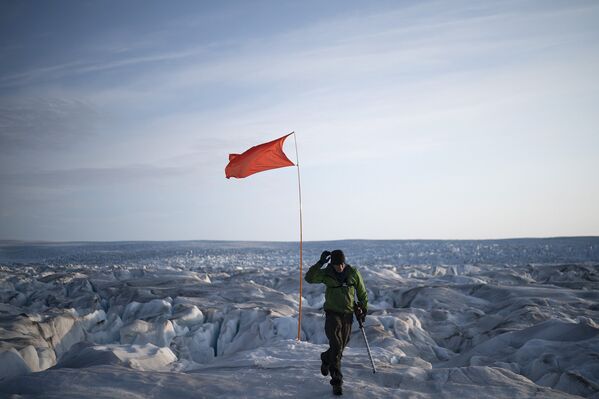 Офицер Брайан Ружо поднимает флаг на гренландском леднике Хельхейм