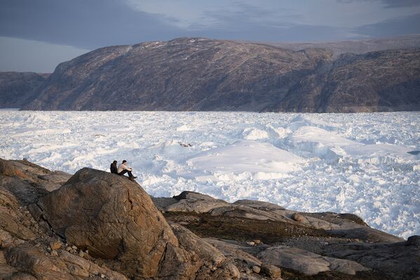 16 августа 2019. Студенты Нью-Йоркского университета сидят на вершине скалы и любуются гренландским ледником Хельхейм