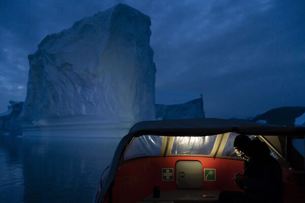 Лодка плывет мимо айсберга, Гренландия