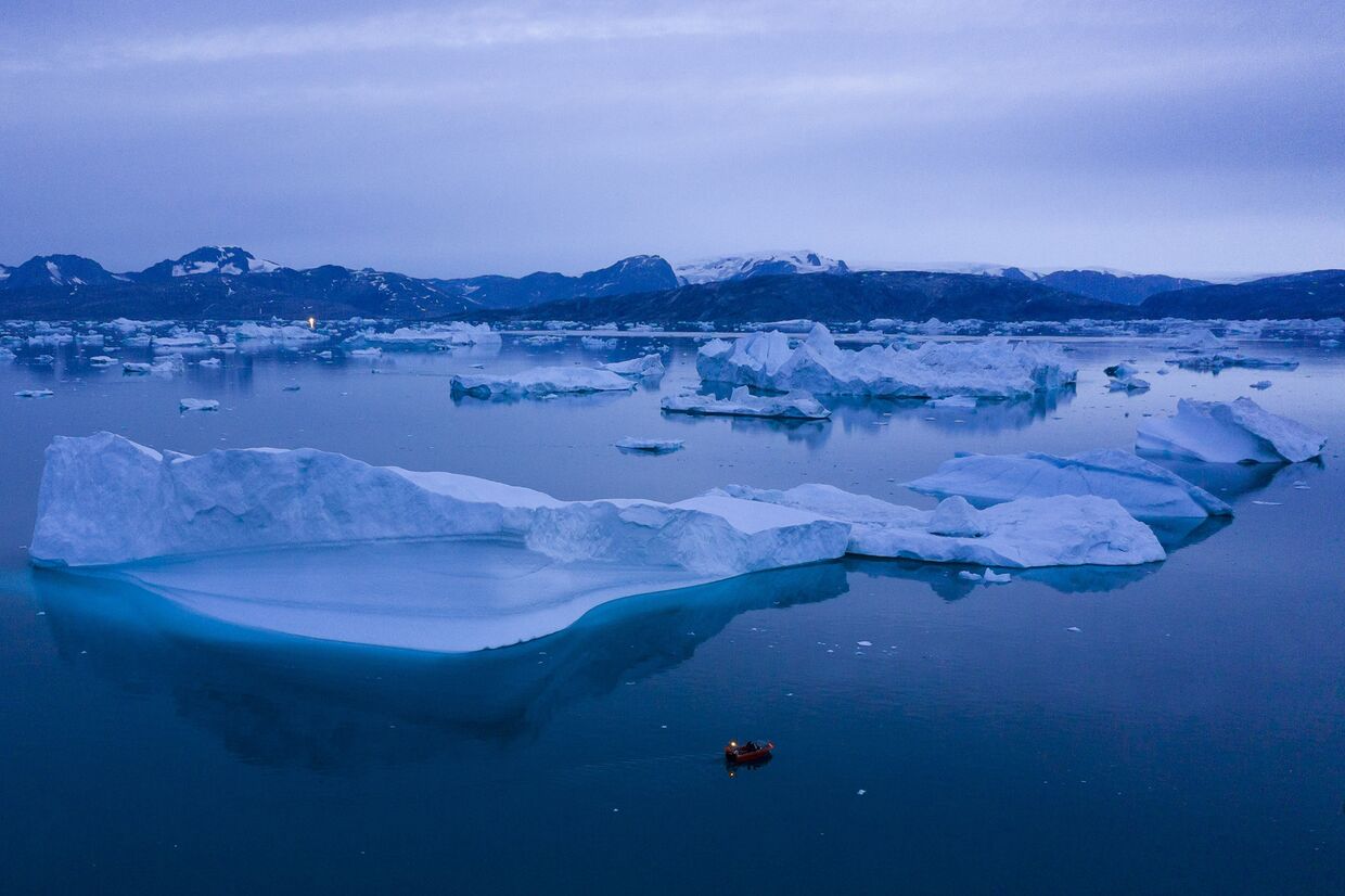 Лодка проплывает мимо айсбергов, Гренландия
