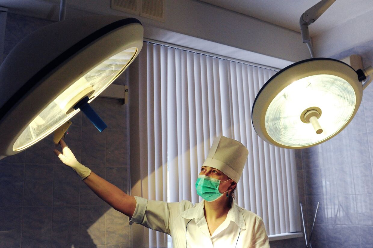 Медицинская сестра устанавливает свет в операционной