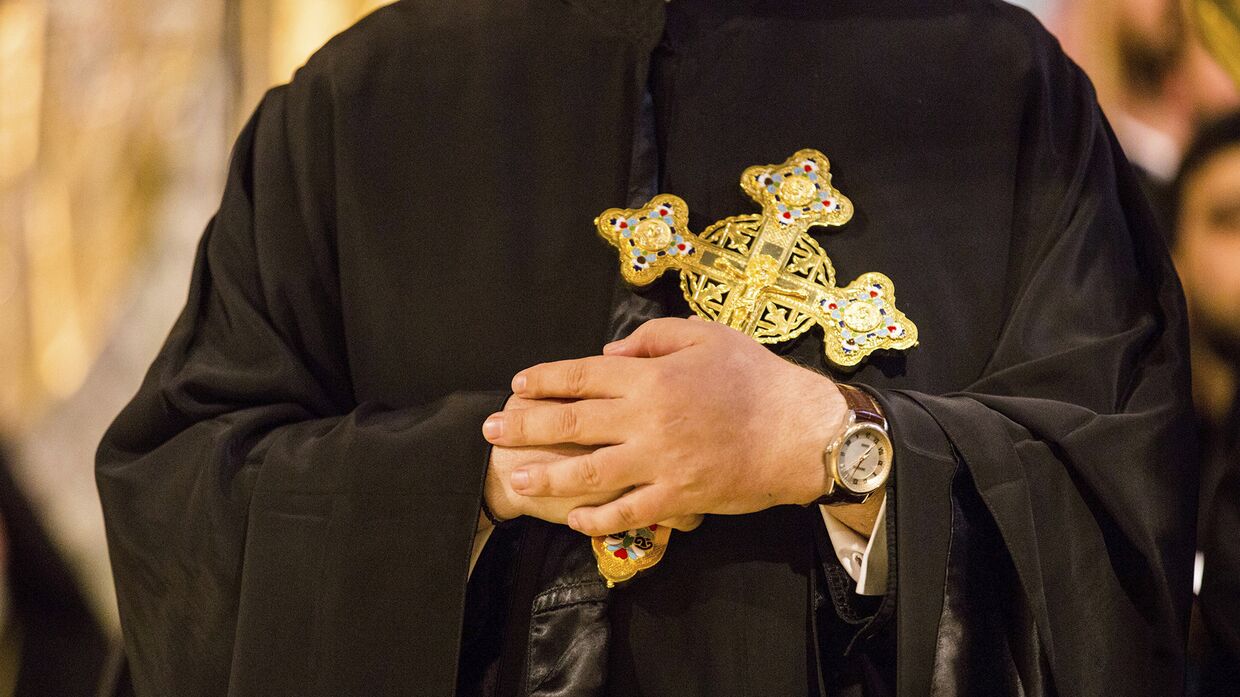 Греческий православный священнослужитель держит крест в архиепископском соборе Святой Троицы в Нью-Йорке