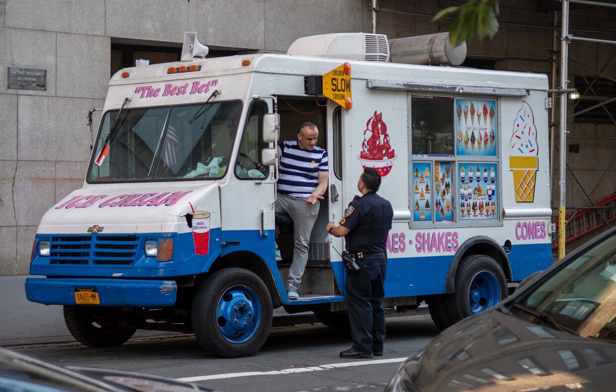 Сотрудник полиции общается с мороженщиком на улице в Нью-Йорке
