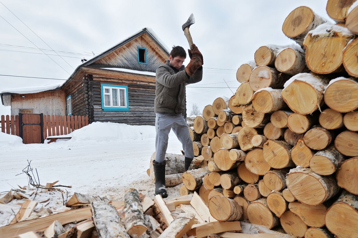 Мужчина рубит дрова в деревне