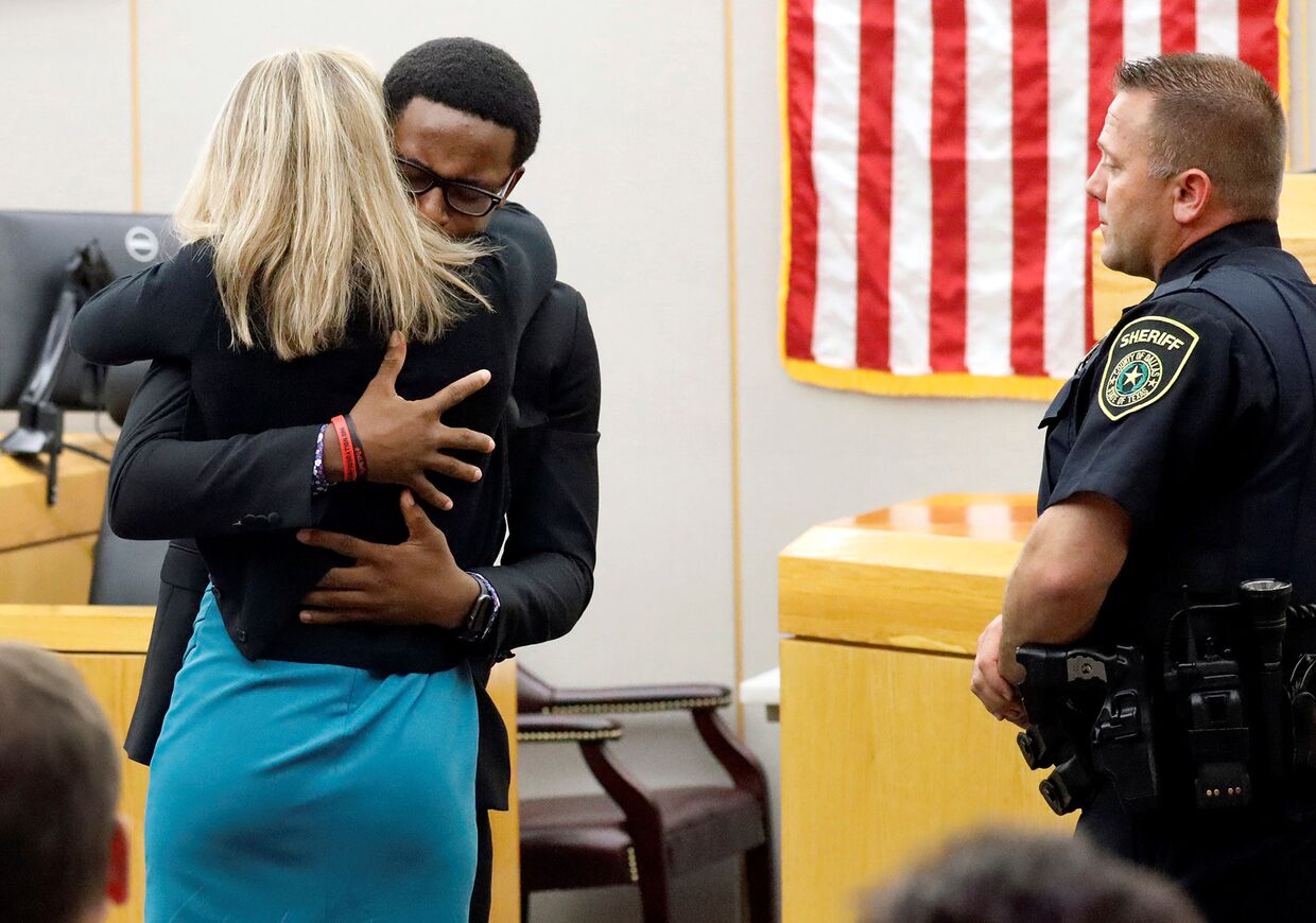 Младший брат убитого обнимает бывшего сотрудника полиции Далласа Эмбер Гайгер на замедании суда в Далласе, штат Техас, США