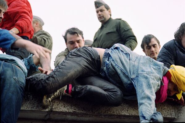 Берлинцы перелезают через Берлинскую стену 11 ноября 1989 года
